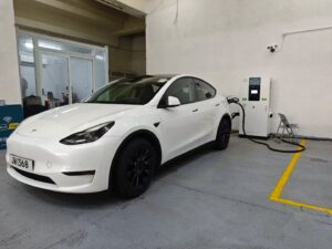 White Tesla Model charging at DC fast charger in indoor charging station